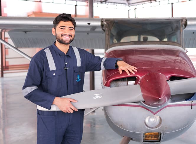 Aerospace Engineering student in flight suit posing with aircraft at Uttaranchal University