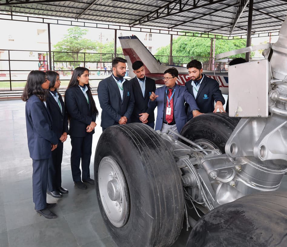 Aerospace Engineering students with faculty examining aircraft landing gear at Uttaranchal University hangar